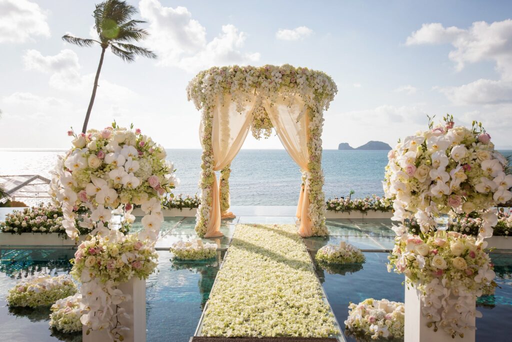 wedding venue aisle in the middle of a moat with white flower styling or decoration and views of the beach in Conrad Koh Samui