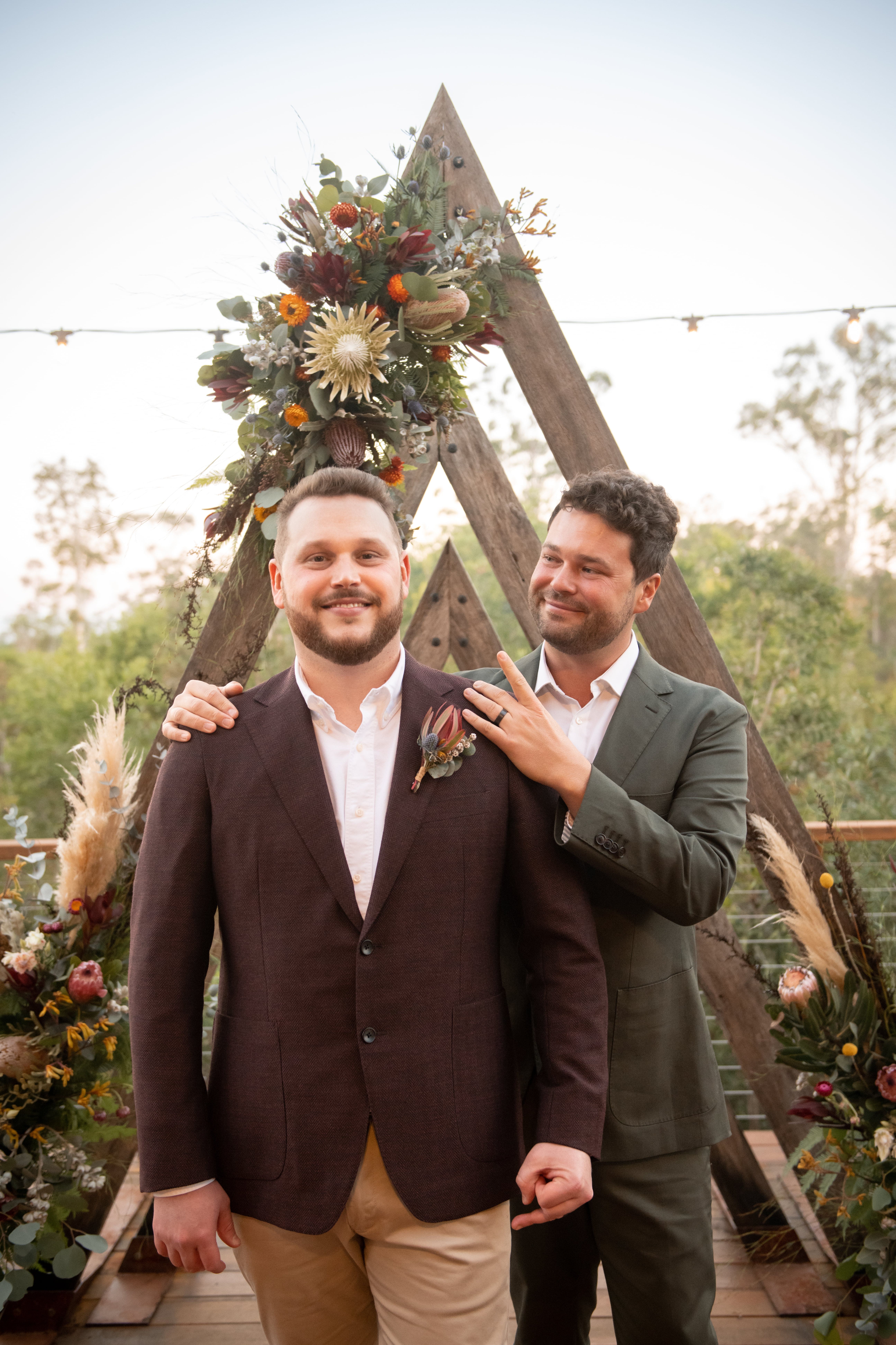 Real-wedding-Luke-and-Mitch-at-The-Crocodile-Lodge-Australia-Zoo-Queensland-newlywedded-couple-portrait-with-wedding-arch-on-the-background