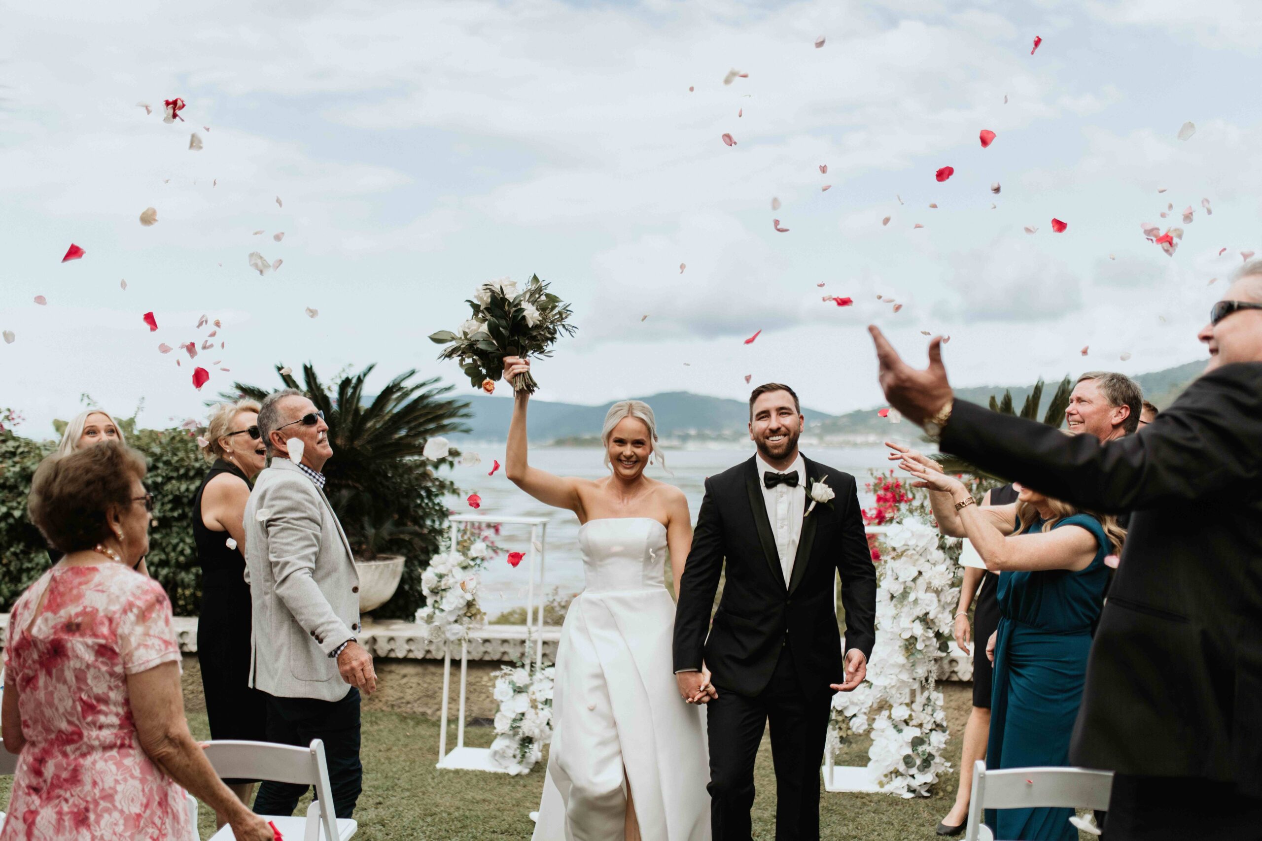 Real-wedding-Teagan-and-Luke-Villa-Botanica-Whitsundays-Australia-by-Rolling-Portraits-newlywed-portrait-post-ceremony-walking-down-the-aisle-with-flower-petals-raining-down