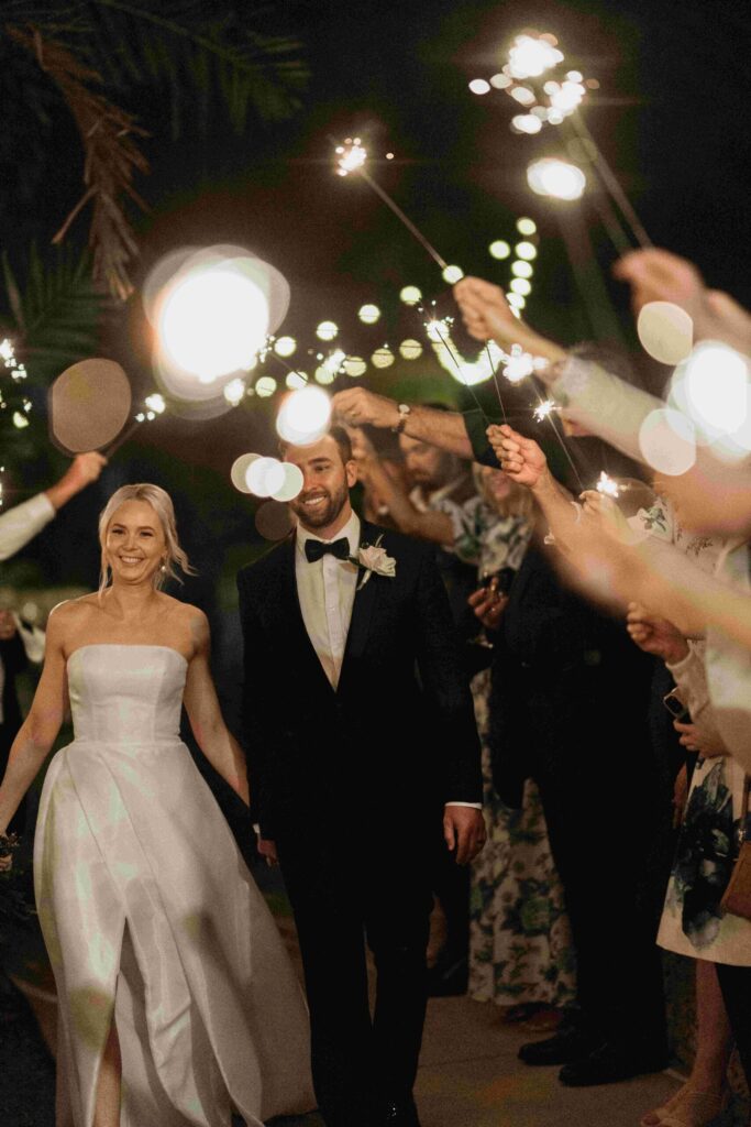 Real-wedding-Teagan-and-Luke-Villa-Botanica-Whitsundays-Australia-by-Rolling-Portraits-newlywed-portrait-post-reception-with-the-guests-holding-sparklers
